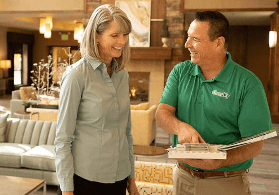 chem-dry technician holding clipboard and speaking with woman in commercial lobby